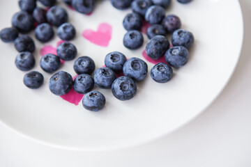 Delicious blueberries lie on a plate with a heart inside. Delicious and healthy food.