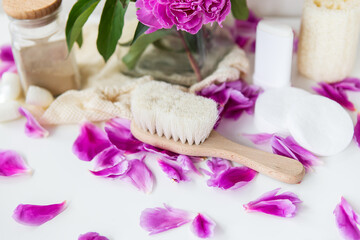 Green lifestyle concept, zero waste. Natural cosmetic. Natural deodorant, massage brush, loofah, reusable bags on a background of peonies. Stop plastic pollution.