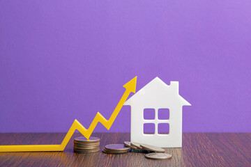 Real estate market, graph, up arrow. House construction model and a stack of coins. The concept of...