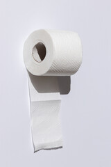 roll of a perforated toilet paper isolated on a white background close-up. hard shadows from the sun at noon