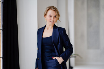 blonde woman in a blue suit poses standing in a photo studio. businesswoman