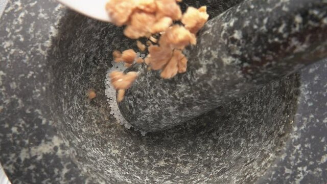 Super close-up of a brown sugar falling into the grey stone mortar