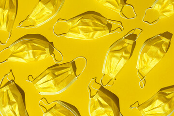 pattern with many golden medical masks isolated on a bright yellow background. hard shadows from the sun at noon