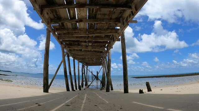 Time lapse white clold blue sky over wooden bridge forward to the sea, botom up view of wooden bride, summer travel concept