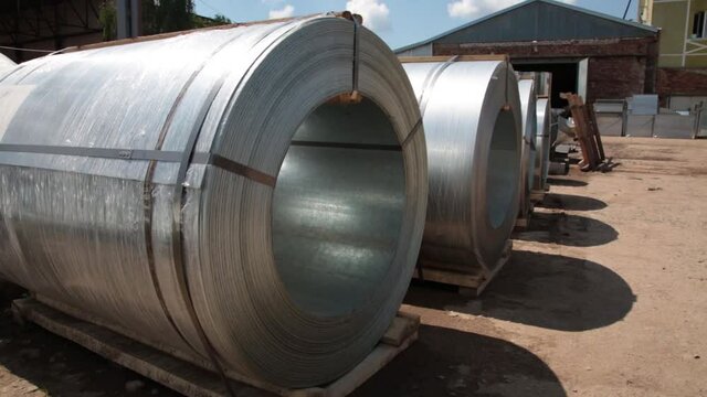 Stainless steel rolls. Rolls of steel sheet in the warehouse. A roll of galvanized steel sheet for the production of metal pipes and tubes in a factory.