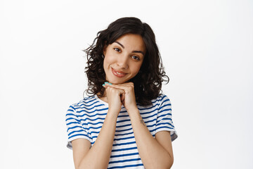 Cute and beautiful young woman, gazing at camera lovely, standing coquettish and coy, flirting with someone, begging, say please, standing over white background