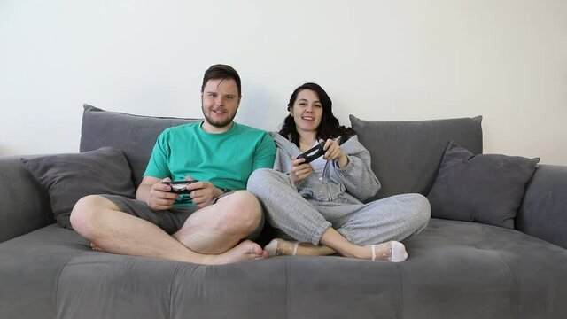 couple together playing video games sitting on couch