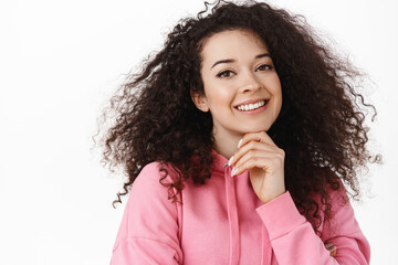 Fototapeta na wymiar Beauty and lifestyle. Young woman with natural glowing skin, curly dark hair, smiling white teeth and looking happy, touch chin thoughtful, have interesting idea, standing against white background