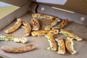 Leftover pizza in a cardboard box on a home table. Unhealthy high-calorie food