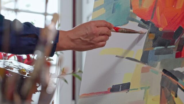 Woman artist applying paint with brush strokes on canvas, brush close-up. Abstract painting.
