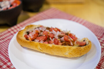 Traditional Mexican mollete on a plate above white and red checkered napkin