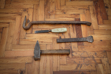 Tools for old damaged parquet removal, hammer, crowbar, chisel at old planks