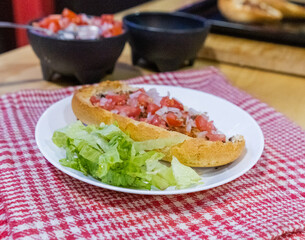 Mexican mollete and lettuce on a plate above white and red checkered napkin