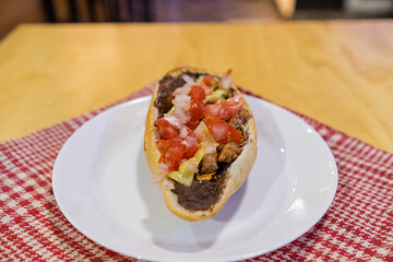 Traditional Mexican mollete on a plate above white and red checkered napkin