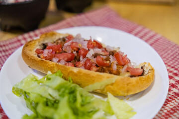 Mexican mollete and lettuce on a plate above white and red checkered napkin