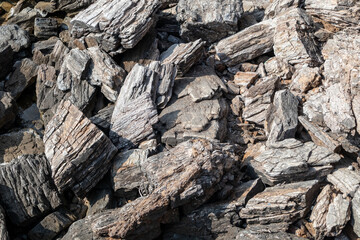 Aegean sea sharp big rocks shore close-up texture. Various rocky surface in sunny Greece near Athens