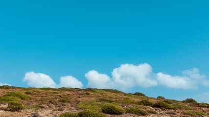 Steppe Greece terrain landscape with scenic cloudscape on blue bright vivid sky. Natural south Europe rocky bushy view