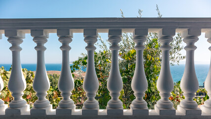 Traditional Greek architecture white balcony balusters. View on clear blue Aegean sea coast. Summer scenic view from country house terrace near Athens, Greece