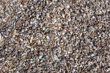 Aegean sea pebble marble stone beach close-up texture. Various rocky surface in sunny Greece near Athens