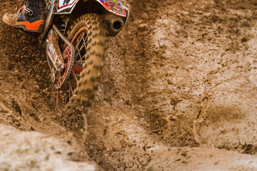 Close up of motocross racer accelerating in dirt track.