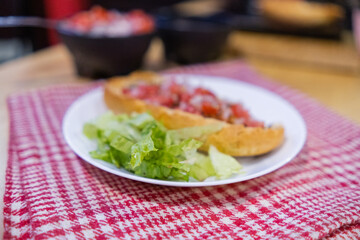 Mexican mollete and lettuce on a plate above white and red checkered napkin
