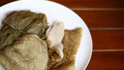 Beef tripe on white plate, wood background. 