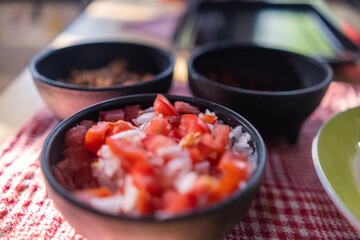 Black bowls of pico de gallo above checkered tablecloth