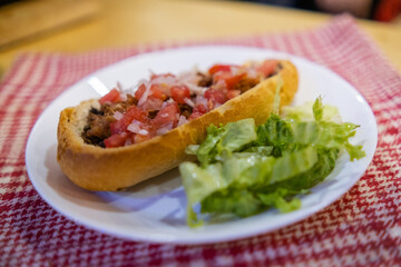 Mexican mollete and lettuce on a plate above white and red checkered napkin