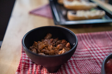 Chopped pork in black bowl above checkered napkin