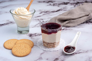 sweet desserts chocotorta and chiskey with cookies sweet milk and red fruit jam in glasses on light marble countertops