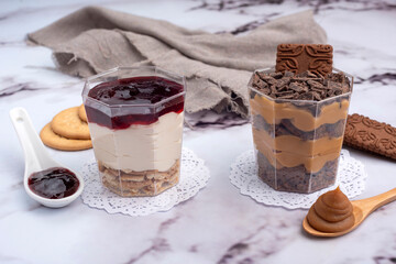 sweet desserts chocotorta and chiskey with cookies sweet milk and red fruit jam in glasses on light marble countertops