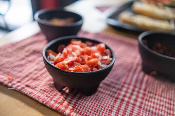 Black bowls of pico de gallo above checkered tablecloth