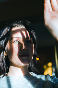 Woman holding hand up to light creating shadow on her face