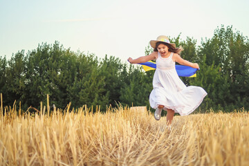 Naklejka na ściany i meble Beautiful girl in hat with Ukrainian flag in wheat field. 4th of July. Fourth of July. Freedom. Independence Day. Patriotic holiday. Flag Day. Constitution day. Copy space