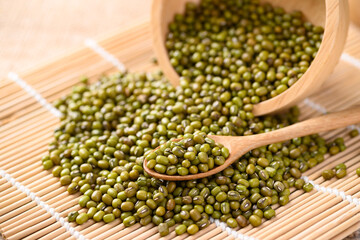 Pile of mung bean seeds in a wooden spoon and bowl, Food ingredients in Asian cuisine and produce mung bean sprout