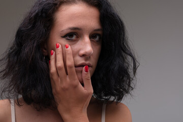 Serious soulful young woman holding her hand to her cheek