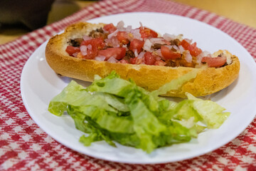 Mexican mollete and lettuce on a plate above white and red checkered napkin