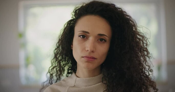 Portrait of a sad looking multi ethnic young woman looking to the camera. Close up, slow motion. 