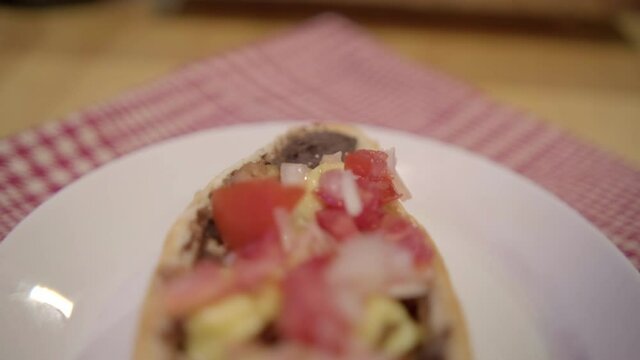 Traditional Mexican mollete on a plate above white and red checkered napkin