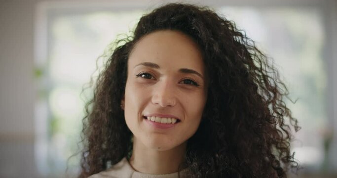 Portrait of a beautiful happy young woman with curly hair smiling. Close up, slow motion. 