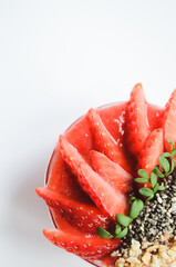 Healthy fresh smoothie bowl with strawberry, tropical fruits, banana, and chia seeds on white wooden table from above. Vegan breakfast concept. Top view