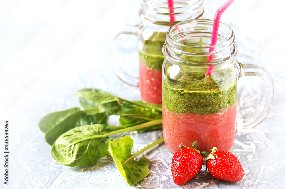 Sticker Two-layered smoothies made of strawberries and spinach in a trendy jar with a handle. Next to fresh strawberries and juicy spinach leaves. organic food. For vegan and raw food nutrition. 