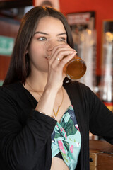 young beautiful woman holding and drinking a drink in a glass tumbler, wears necklace and casual clothes, modern female model beauty and fashion