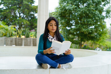 MUJER JOVEN HISPANA SENTADA LEYENDO LIBRO EN POPAYÁN, COLOMBIA