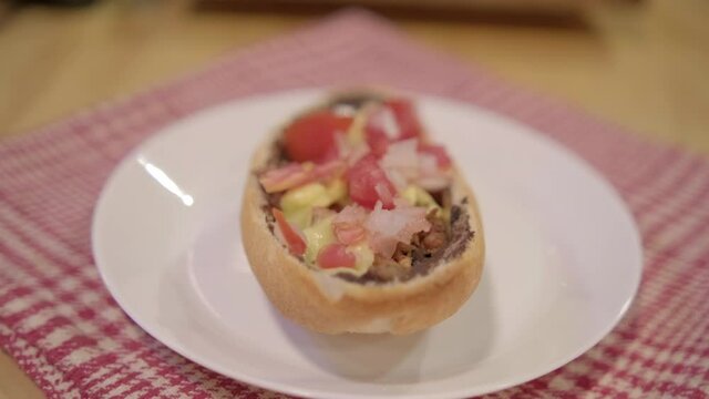 Traditional Mexican mollete on a plate above white and red checkered napkin