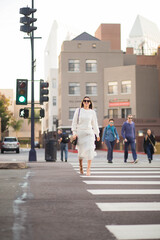 Adult happy woman crossing the street in the city.