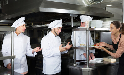 Fototapeta na wymiar young chef of restaurant with team of cooks busy to preparing food for they client