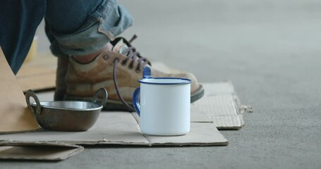 Close up on the cup of homeless man which people giving coin money