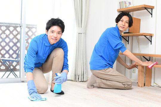 部屋で掃除をする清掃業の作業服の複数の若い男性
