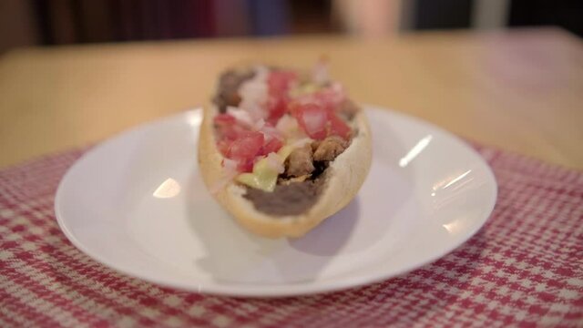 Traditional Mexican mollete on a plate above white and red checkered napkin
